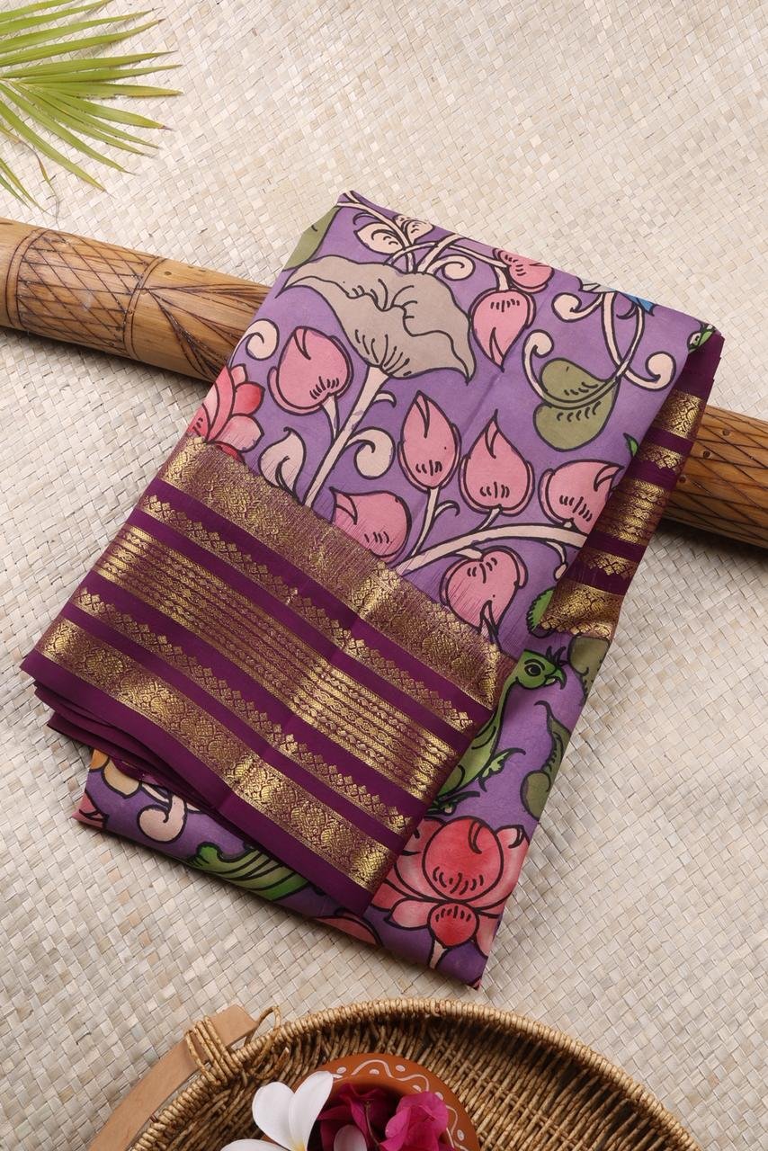 Stunning, graceful, and artistic — this dual-toned saree in shades of lavender and deep purple is a true reflection of timeless craftsmanship. The beautifully blended base creates a rich visual appeal, while the intricate hand-painted Pen Kalamkari designs bring heritage artistry to life. Each motif is carefully crafted, showcasing traditional storytelling elements and fine detailing that make this saree unique and captivating. The harmonious combination of soft lavender and bold deep purple adds depth, elegance, and a distinctive charm to the overall look. Crafted for both comfort and style, this saree offers a smooth texture and an effortless drape, making it an excellent choice for festive occasions, cultural gatherings, and special celebrations. Pair it with classic or statement jewelry to complete a refined and eye-catching ensemble. Key Features: Unique dual-tone combination of lavender and deep purple Authentic hand-painted Pen Kalamkari artwork Intricate traditional motifs with artistic detailing Smooth, comfortable fabric with graceful drape Ideal for festive wear and cultural occasions