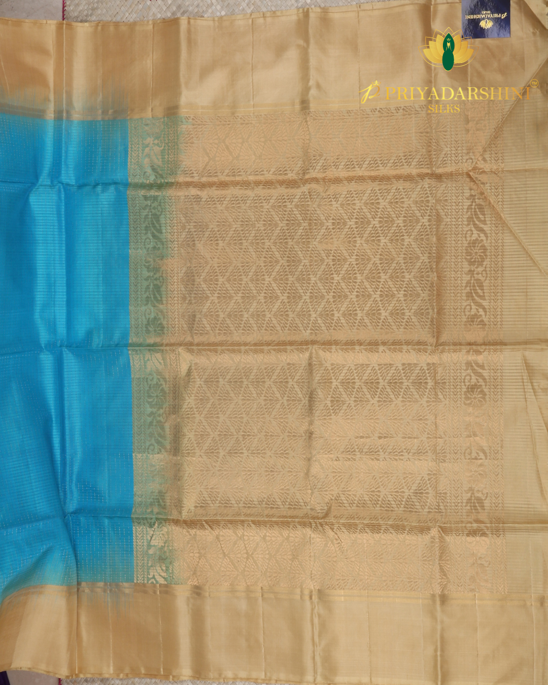 Experience the beautiful contrast of a vibrant aqua blue body meeting a majestic antique gold beige border and pallu. This premium soft silk saree features delicate metallic stripes and timeless traditional motifs.
